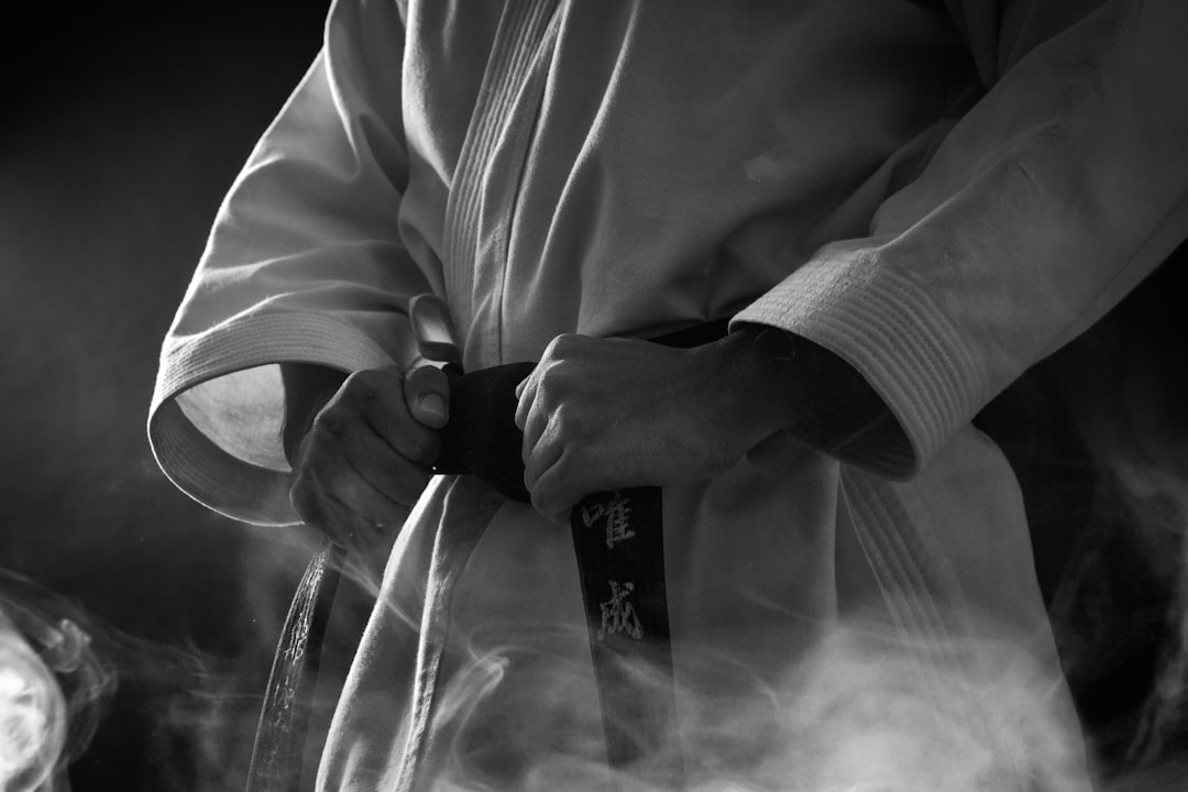 A person in a white martial arts gi tightening a black belt