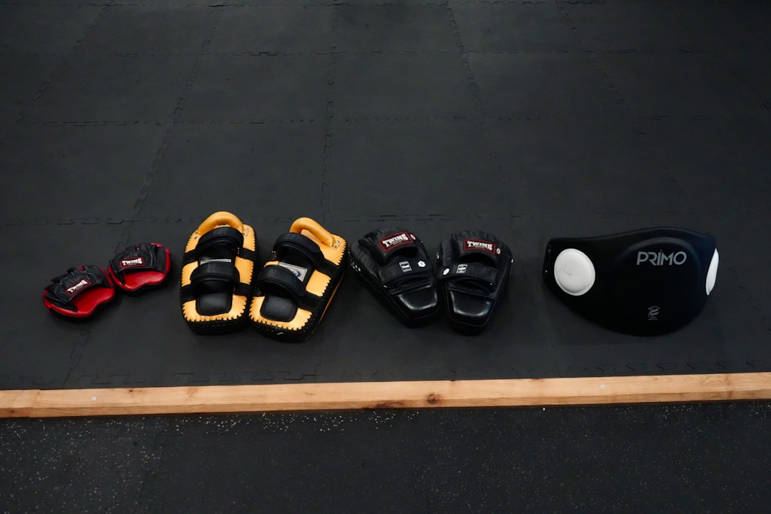 Various martial arts protectors and headgear on a dark mat